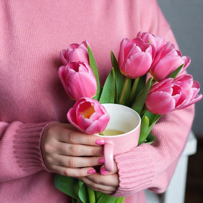 Woman holding pink tulips and teacup