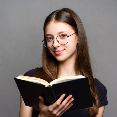 Young woman reading book with glasses