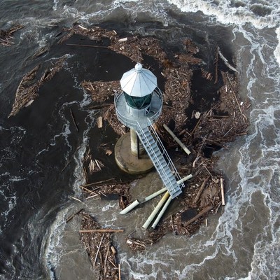 Lighthouse surrounded by debris and waves