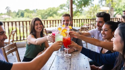 Diverse group toasting colorful cocktails outdoors