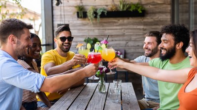 Diverse group toasting colorful cocktails outdoors