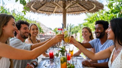 Diverse group toasting cocktails under thatched roof