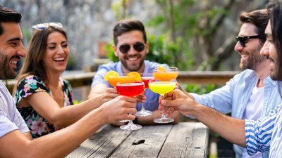 Friends cheering with colorful cocktails outdoors