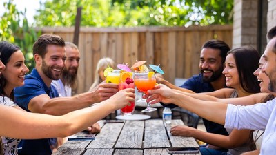 Group toasting with colorful cocktails outdoors