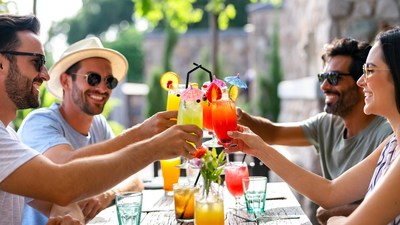 Friends cheering with colorful cocktails outdoors