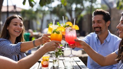 Group toasting colorful cocktails outdoors