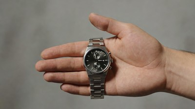 Man's hand holding silver chronograph watch