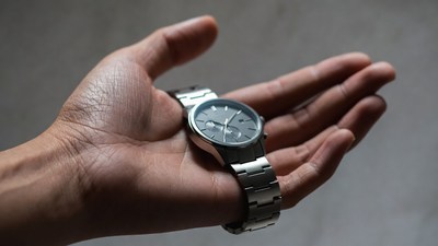 Man's hand holding silver watch