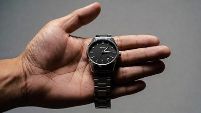 Man's hand holding black wristwatch