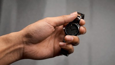 Man's hand holding black wristwatch