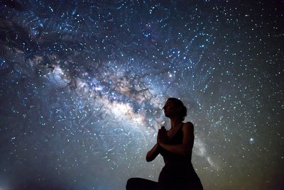Woman praying silhouette under Milky Way