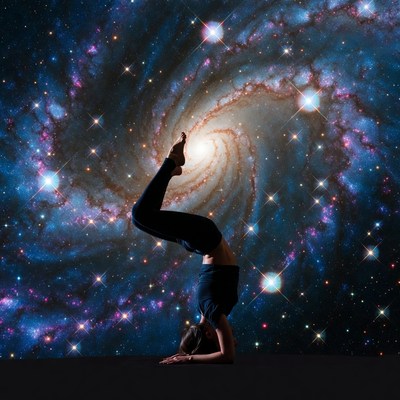 Woman in yoga headstand against galaxy