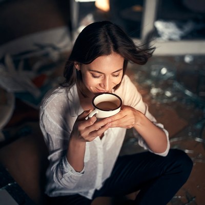 Woman sipping tea amid broken glass