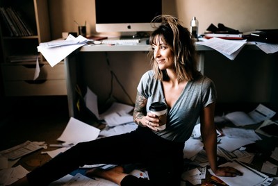 Woman holding coffee in messy office