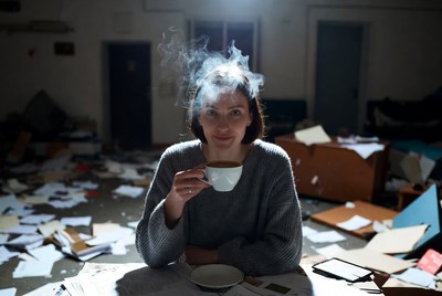 Woman drinking tea in messy room