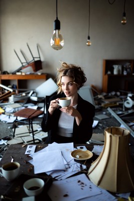 Woman drinking coffee in messy office