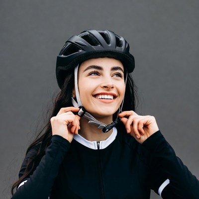 Smiling woman adjusting bike helmet