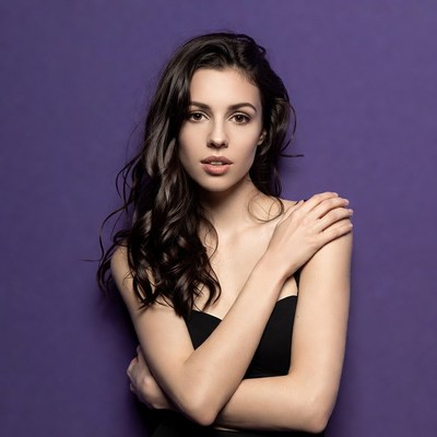 Woman with arms crossed on purple background