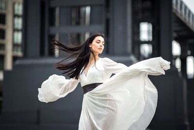 Woman dancing in white dress by bridge