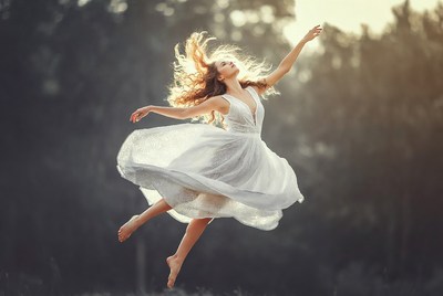 Woman dancing in white dress forest