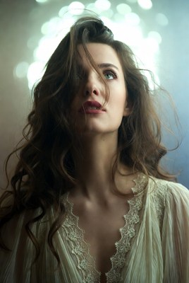 Woman with flowing brown hair and lace blouse