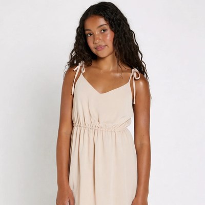 Young Black girl in beige spaghetti strap dress
