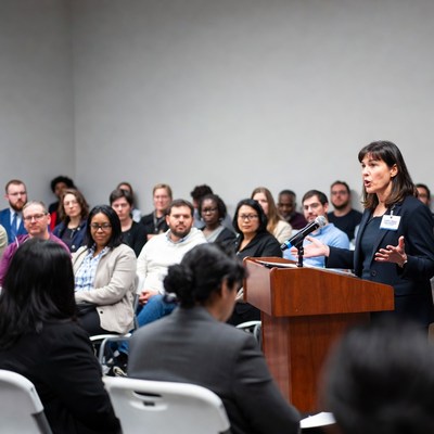 Woman speaking at podium to audience