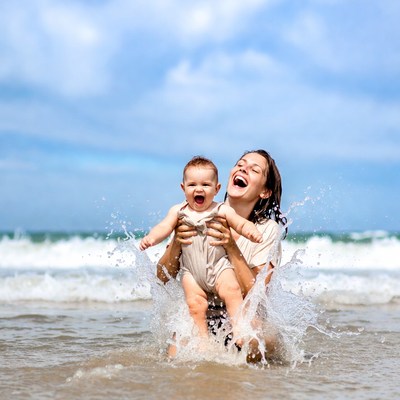 Mother and baby laughing in ocean waves