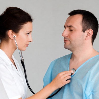 Nurse checking man's heartbeat with stethoscope
