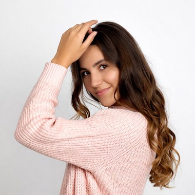 Young woman touching hair in pink sweater