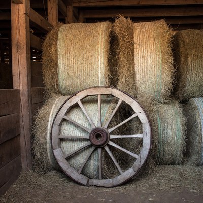 Wooden Wheel with Hay Bales in Barn