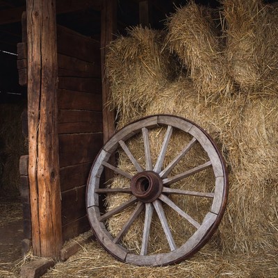 Old wagon wheel against hay bales