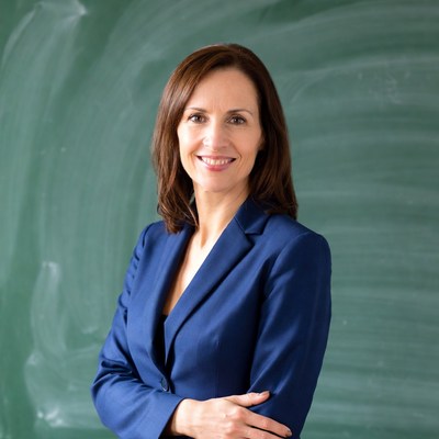 Smiling woman in blue suit by chalkboard
