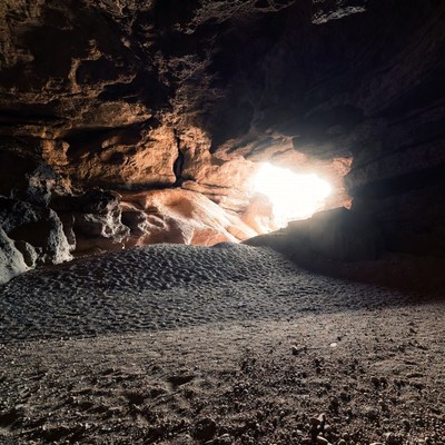 Sunlit Cave Entrance with Sandy Floor
