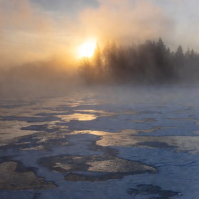 Sunrise over icy foggy lake