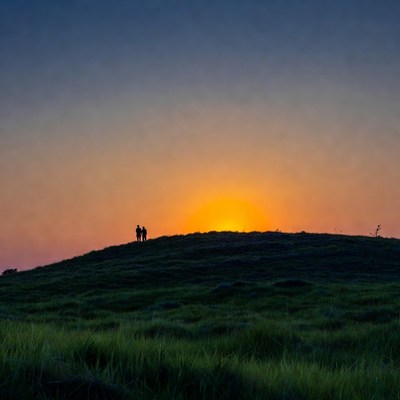 Silhouette couple watching sunset on hill