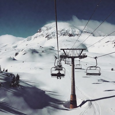 Person riding ski lift snowy mountains