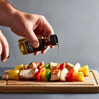 Man pouring olive oil on chicken skewers