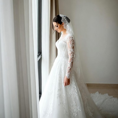 Bride in lace wedding gown by window
