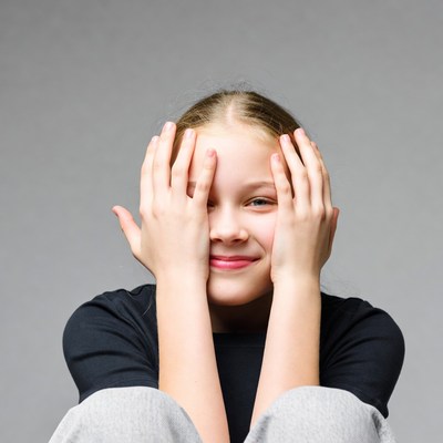 Girl peeking through fingers smiling