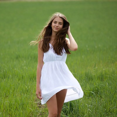 Young woman in white dress in green field