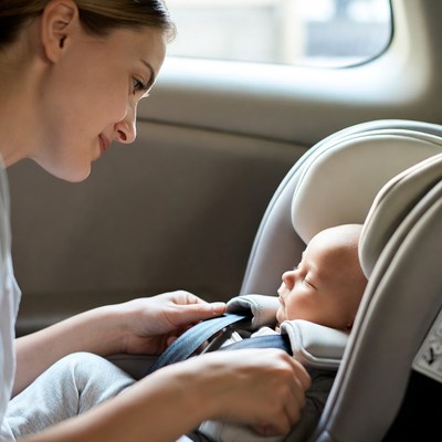Mother buckling baby in car seat