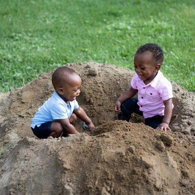 Two African boys playing in sand pile