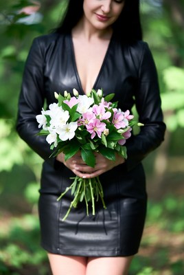 Woman holding flowers in black leather dress