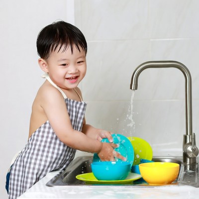 Asian toddler washing dishes