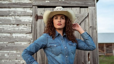 Woman in cowboy hat by barn