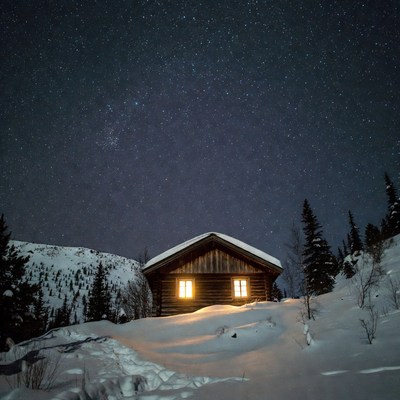 Cozy cabin glowing under starry snowy night