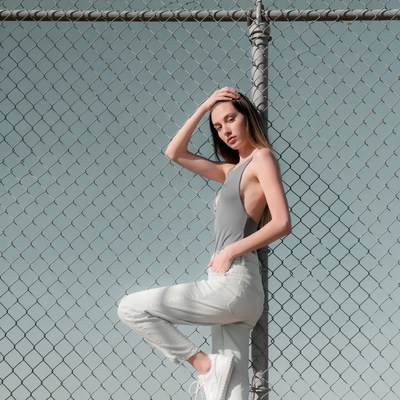 Woman posing against chain link fence