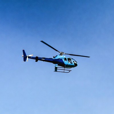 Blue helicopter flying in sky