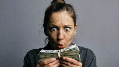 Surprised woman holding cash stack